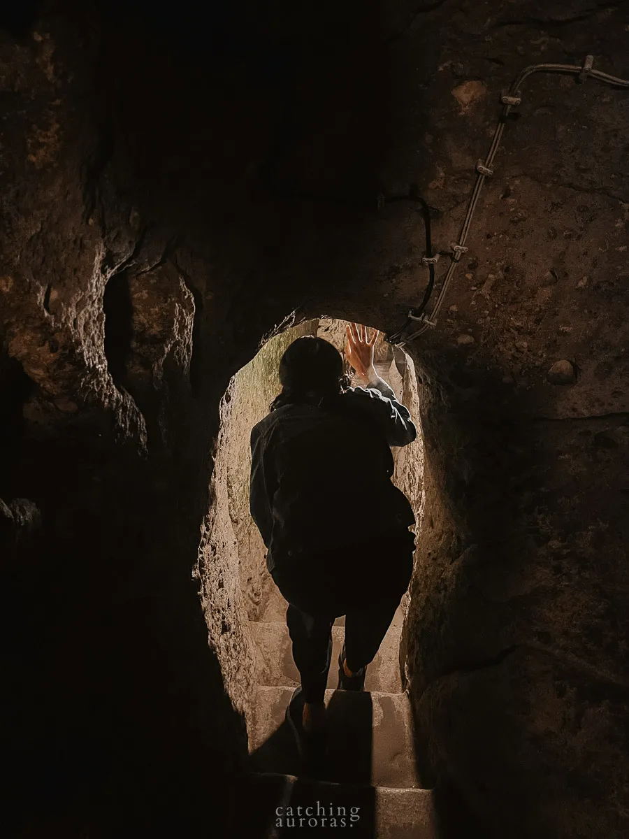 A girl bends to fit through a doorway in Derinkuyu Underground City