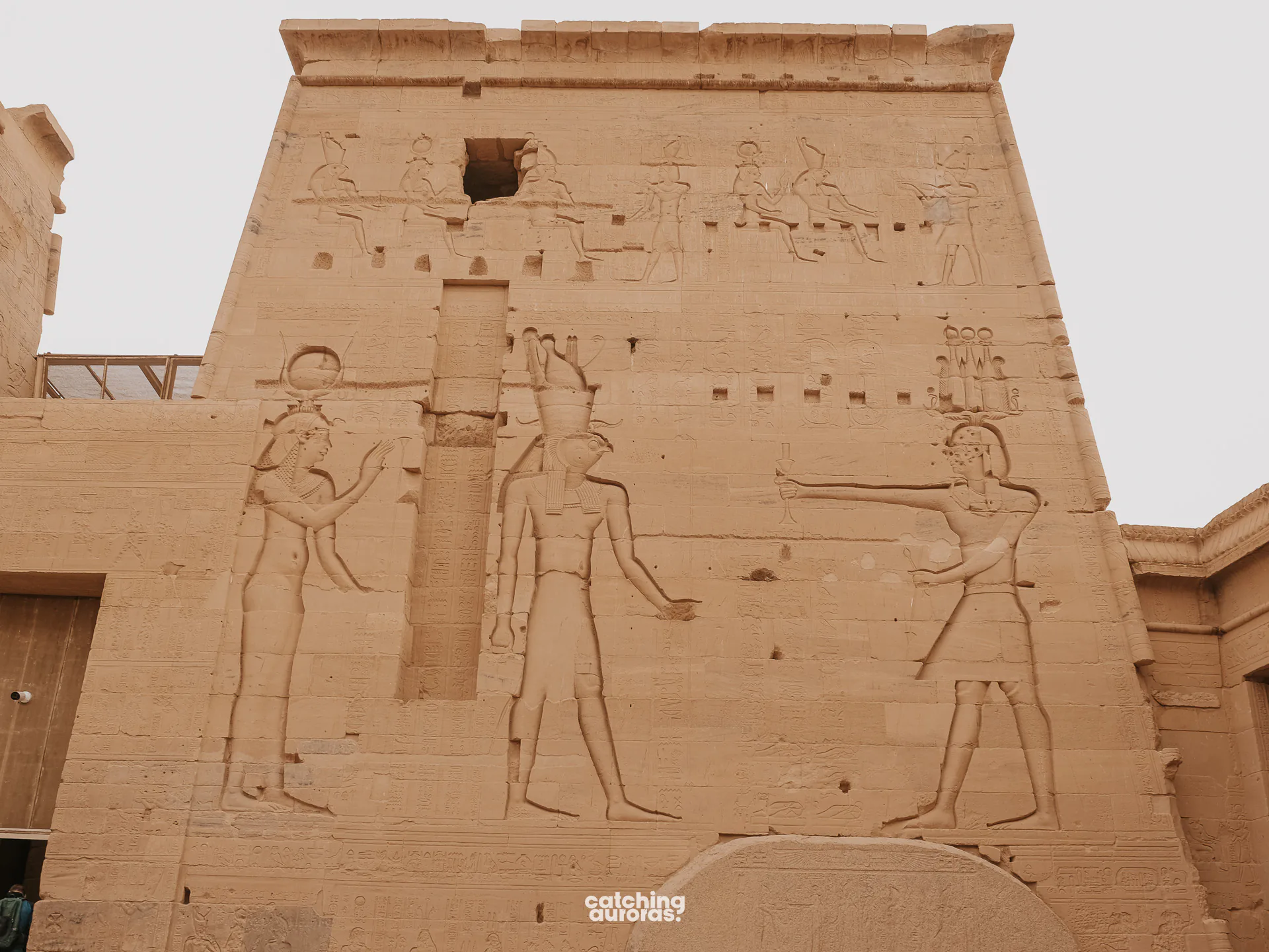 Close-up of carved hieroglyphs and painted reliefs on a wall at Philae Temple, Aswan, Egypt.