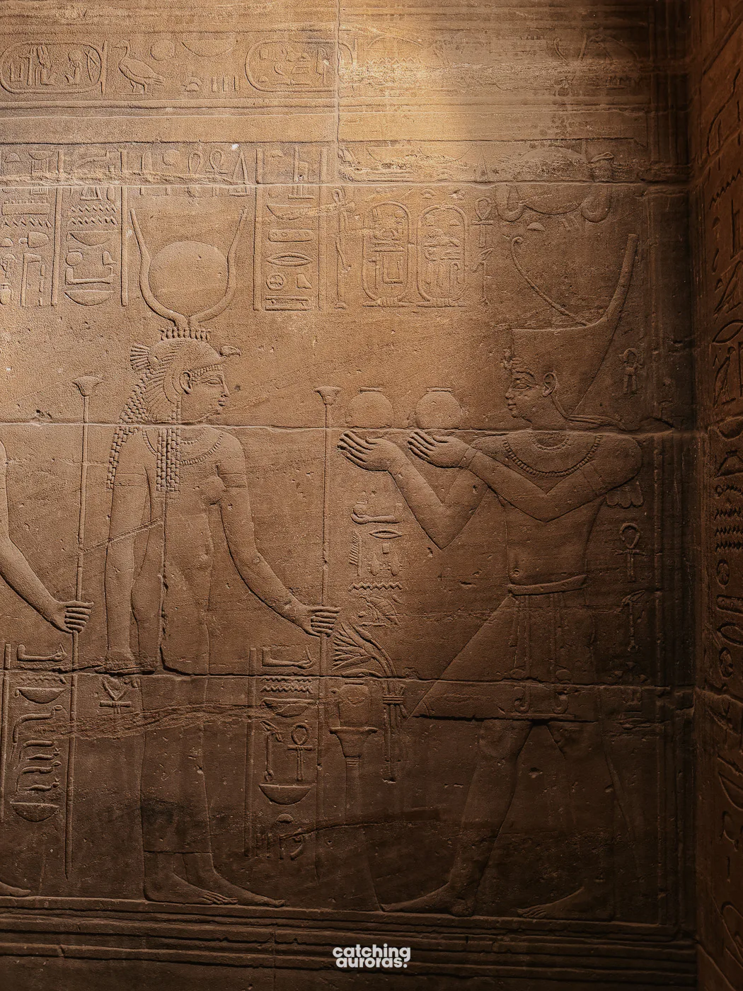 Close-up of carved hieroglyphs and painted reliefs on a wall at Philae Temple, Aswan, Egypt.