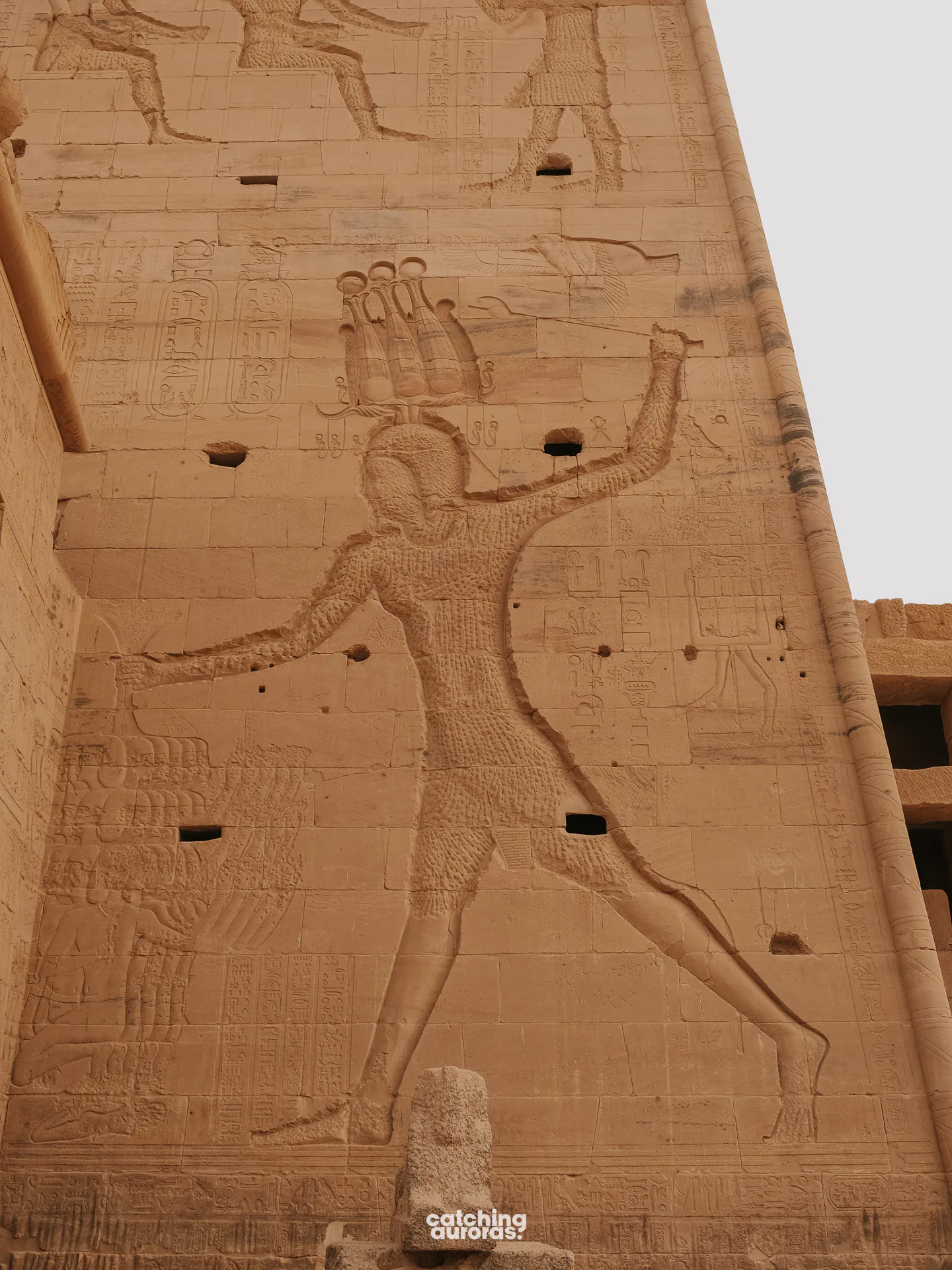 Close-up of Ptolemy XII smiting enemies on a wall at Philae Temple, Aswan, Egypt.