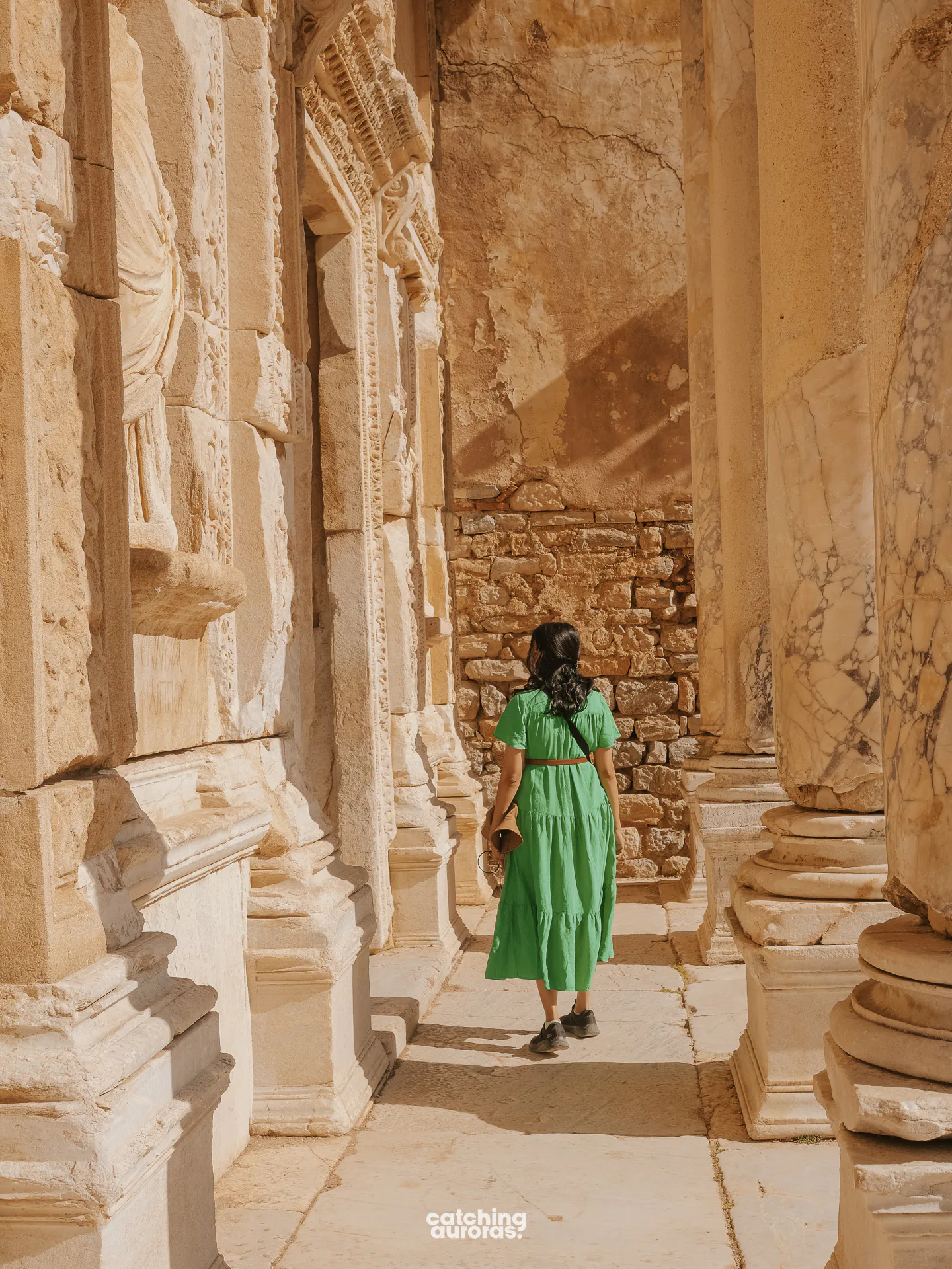 A girl in a green dress walking in the Library of Celsus in Ephesus Ancient City