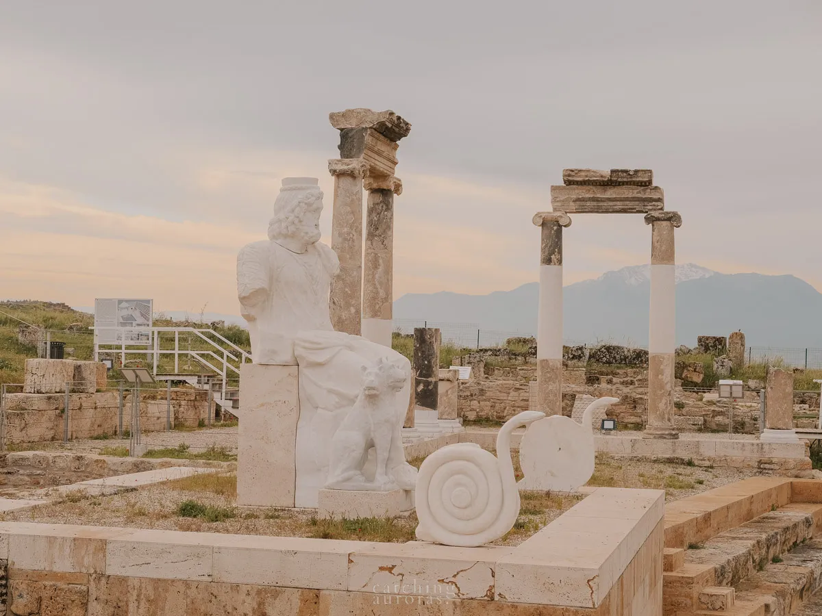 A statue of Pluto, Cerberes and two snakes amidst other ruins