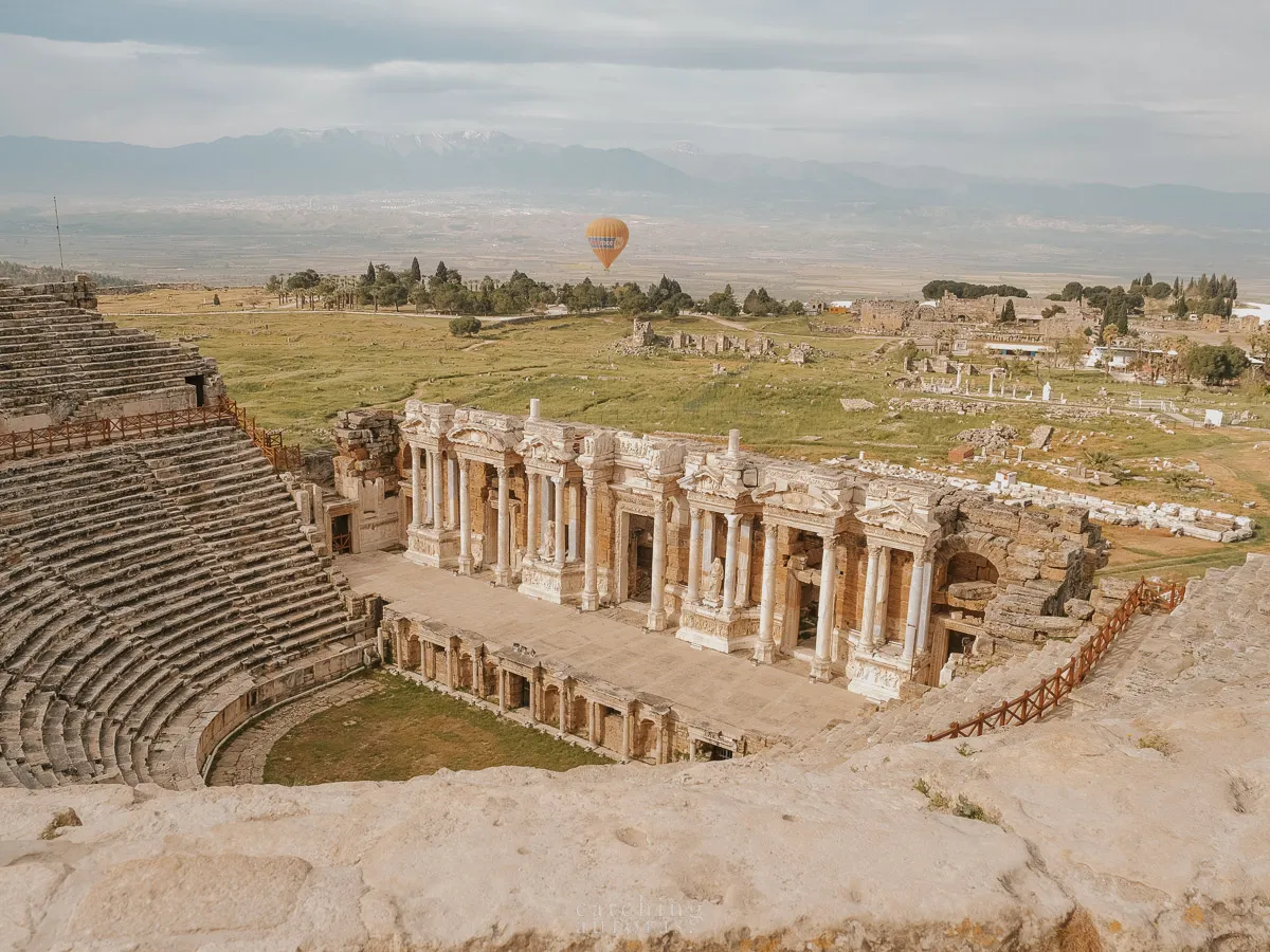 A closer look at the Pamukkale amphitheatre with a balloon flying behind.