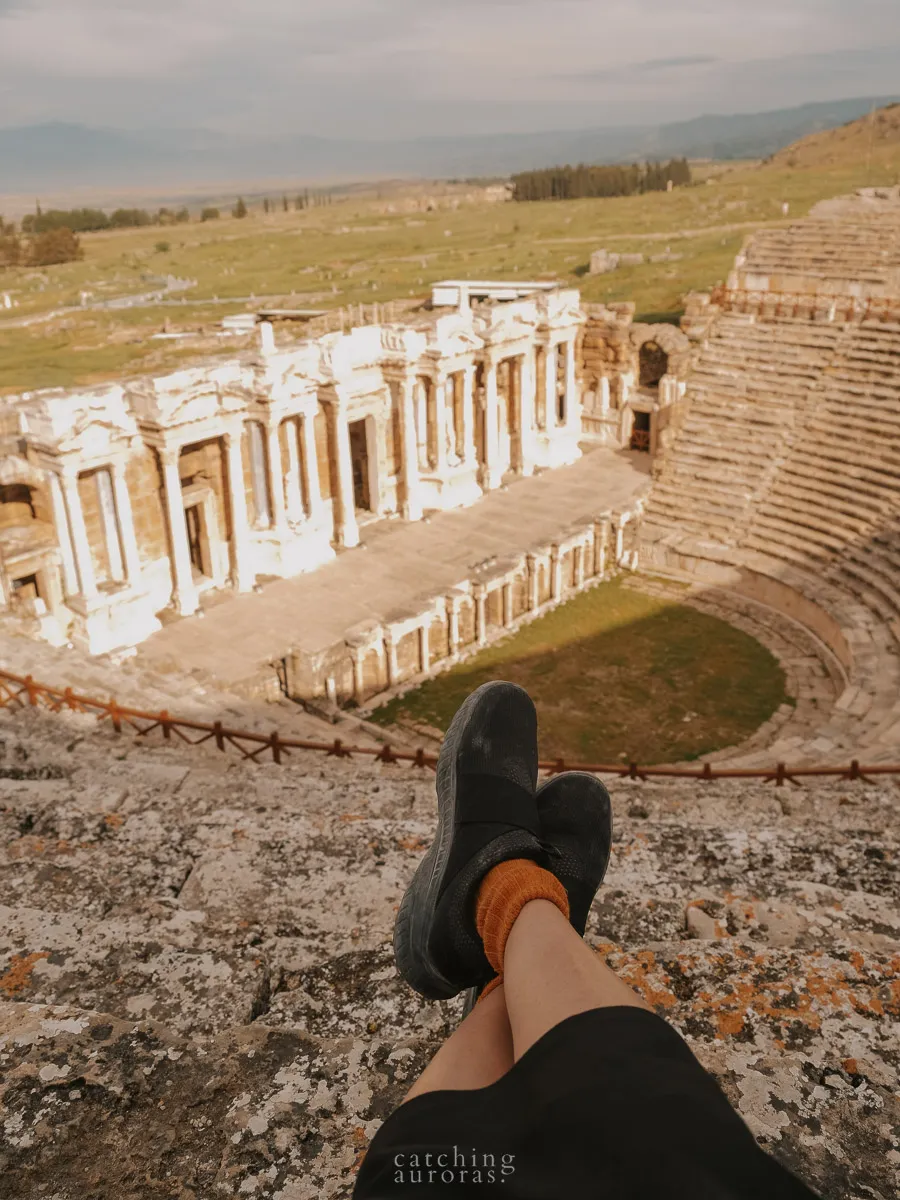 A pair of legs is seen of the photographer looking over the amphitheatre