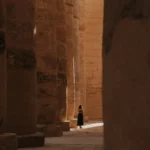 A girl walks amidst the columns of the Hypostyle Hall in Karnak Temple, Luxor