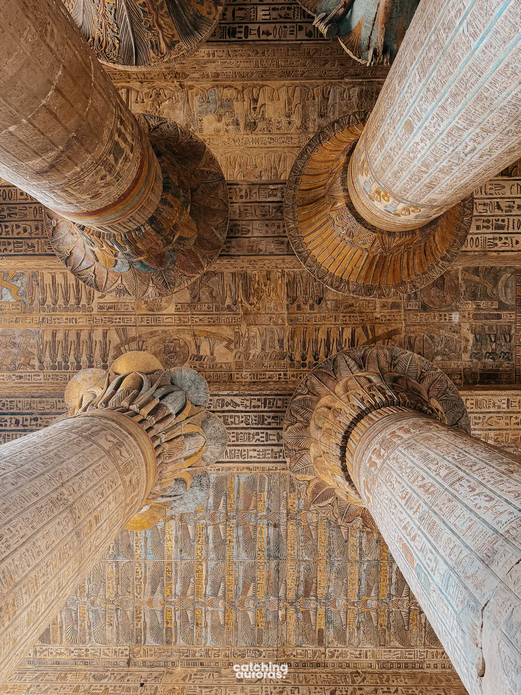 Painted columns inside Esna Temple, covered in colourful figures and hieroglyphs