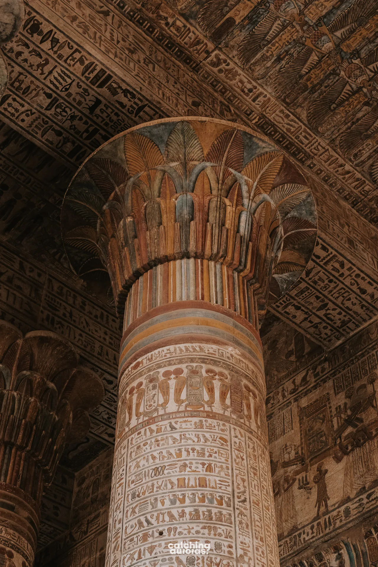 Painted columns inside Esna Temple, covered in colourful figures and hieroglyphs.