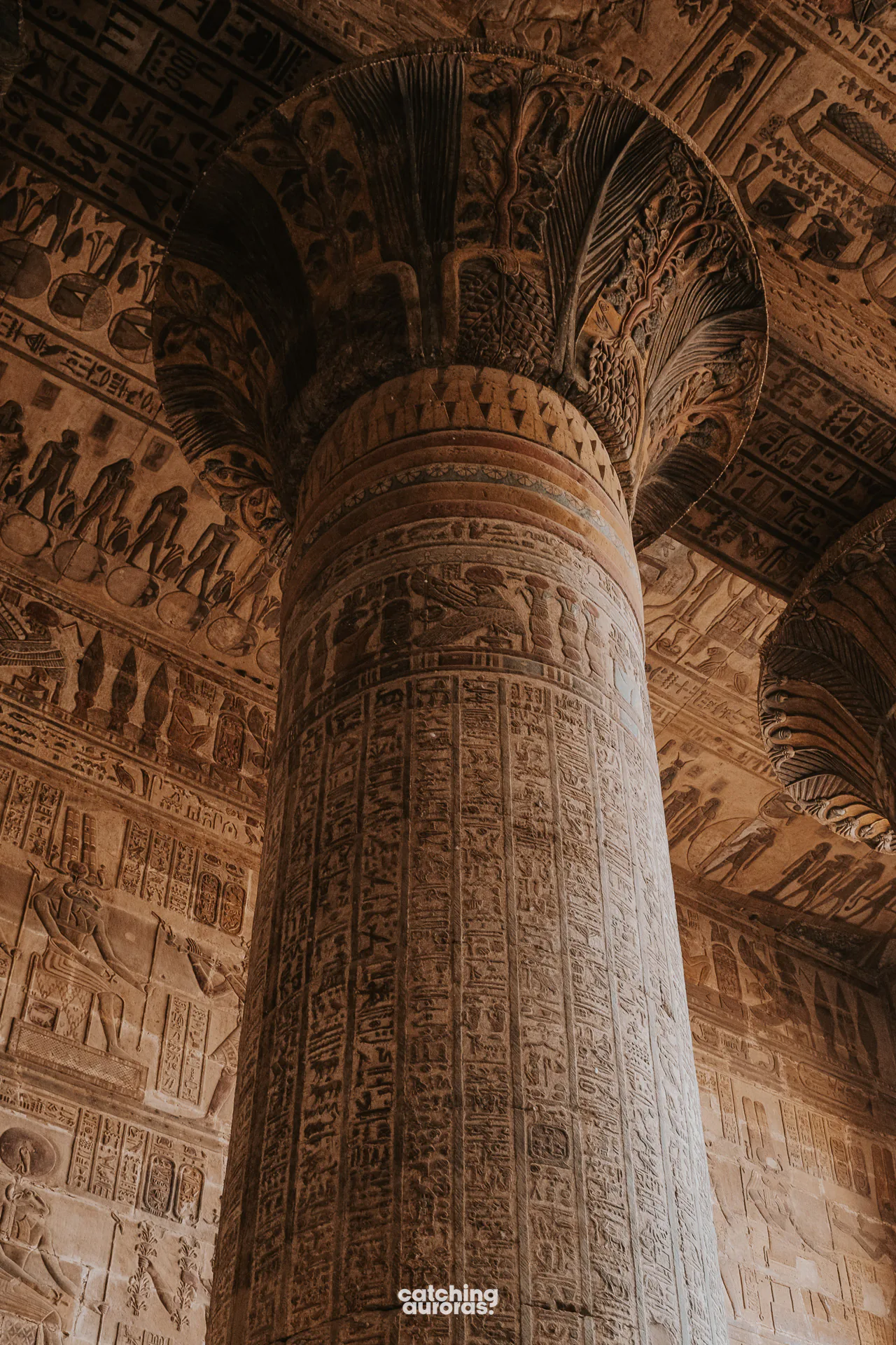 Painted columns inside Esna Temple, covered in colourful figures and hieroglyphs.