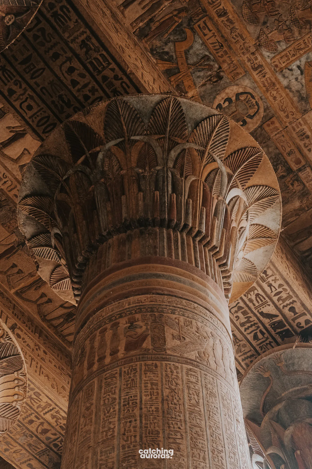 Painted columns inside Esna Temple, covered in colourful figures and hieroglyphs.