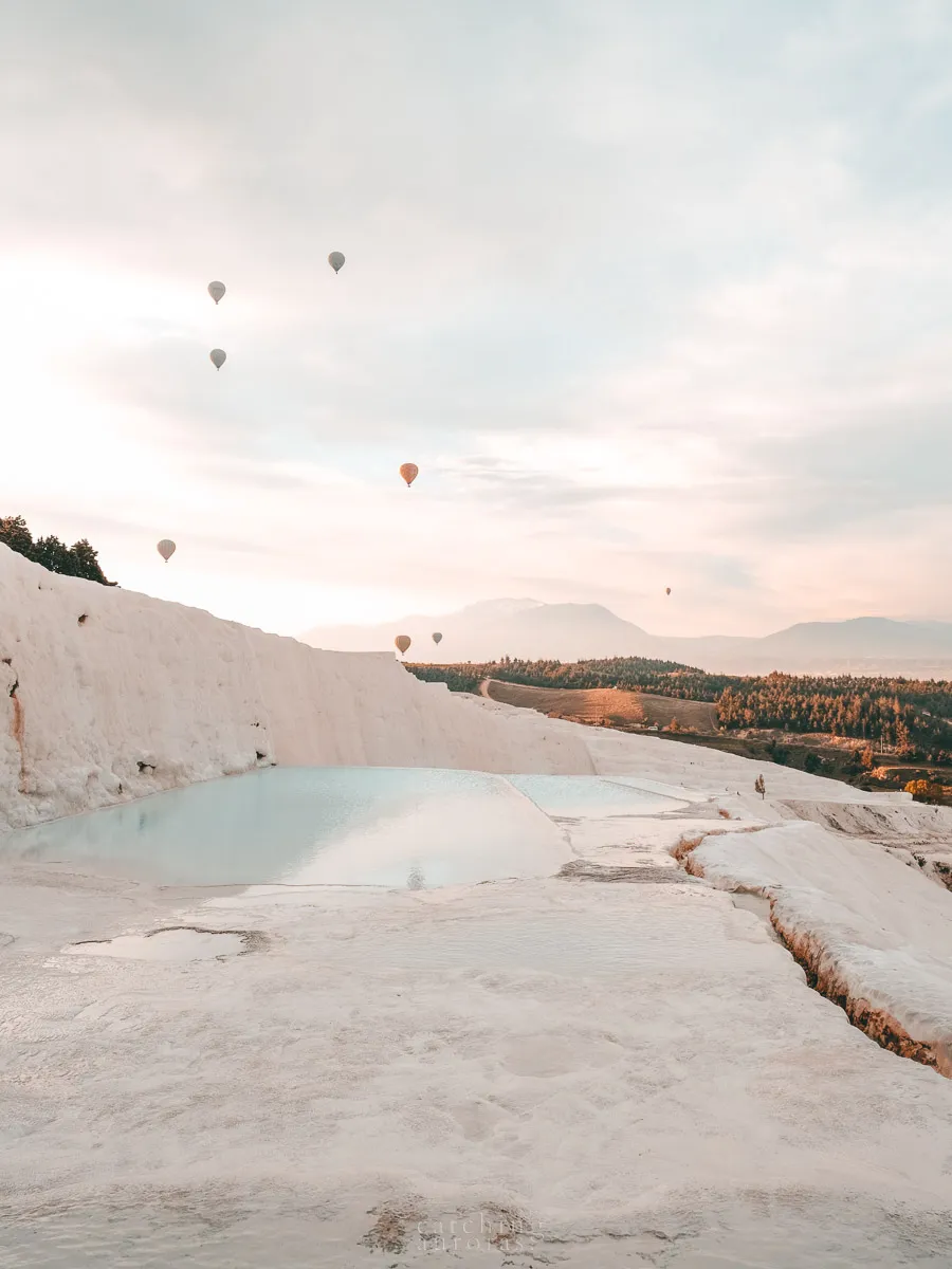 Hot-air balloons flying over Pamukkale’s white travertine terraces at sunrise