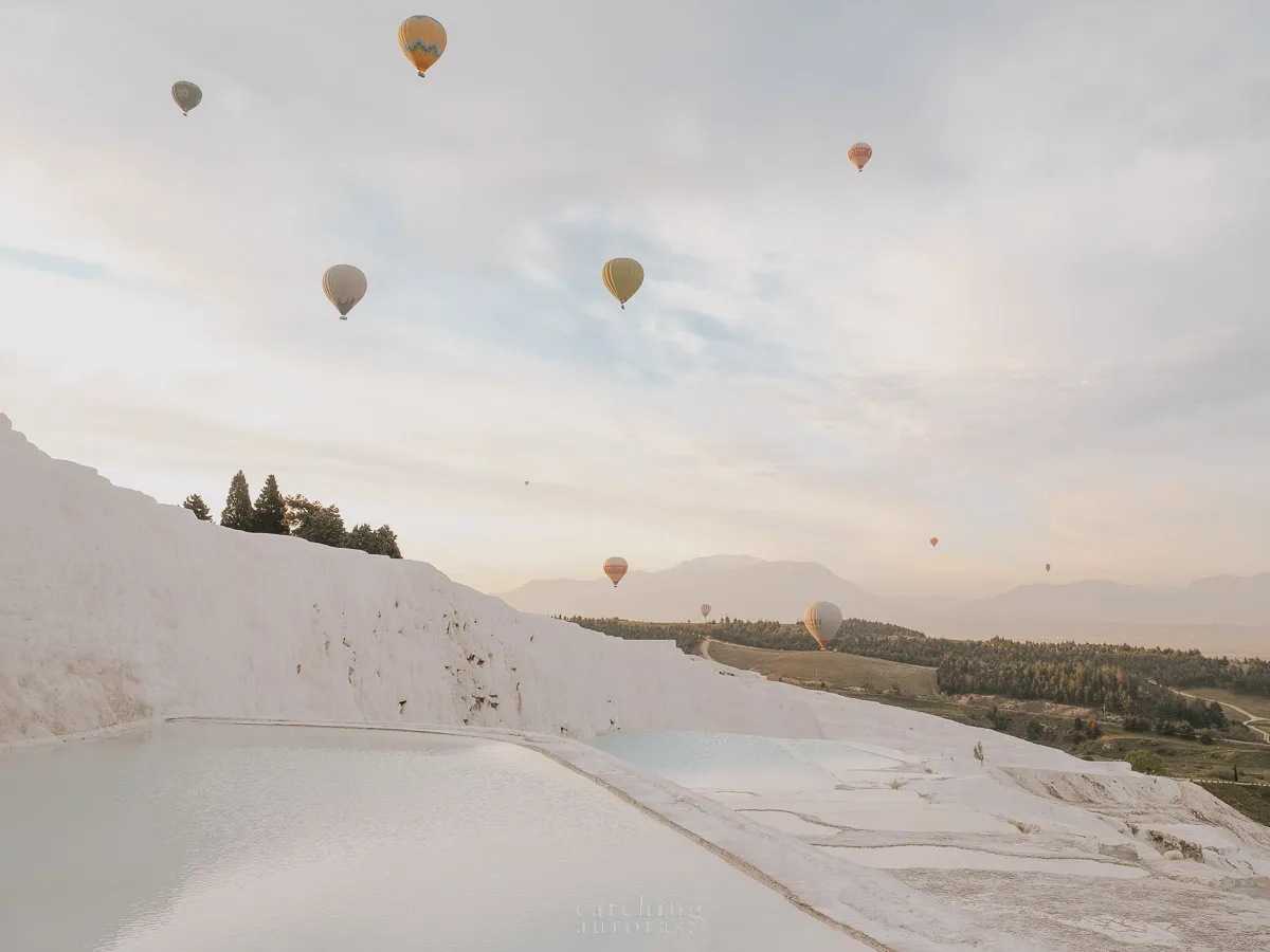 Pamukkale travertines with hot air balloons flying in the background