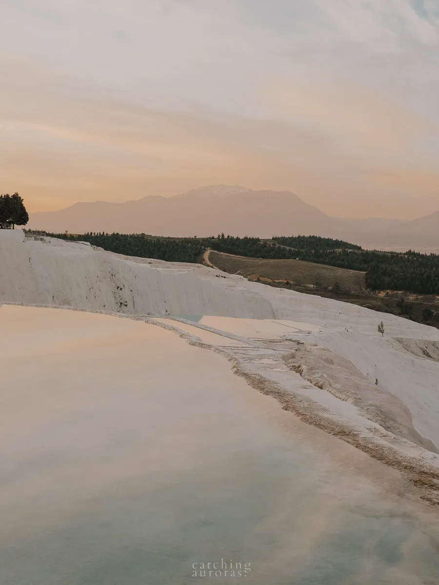 Blue pools of water on a white terrace with sun rising in the background