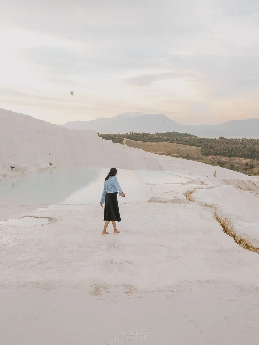 A girl stands on a white terrace with blue pools of water