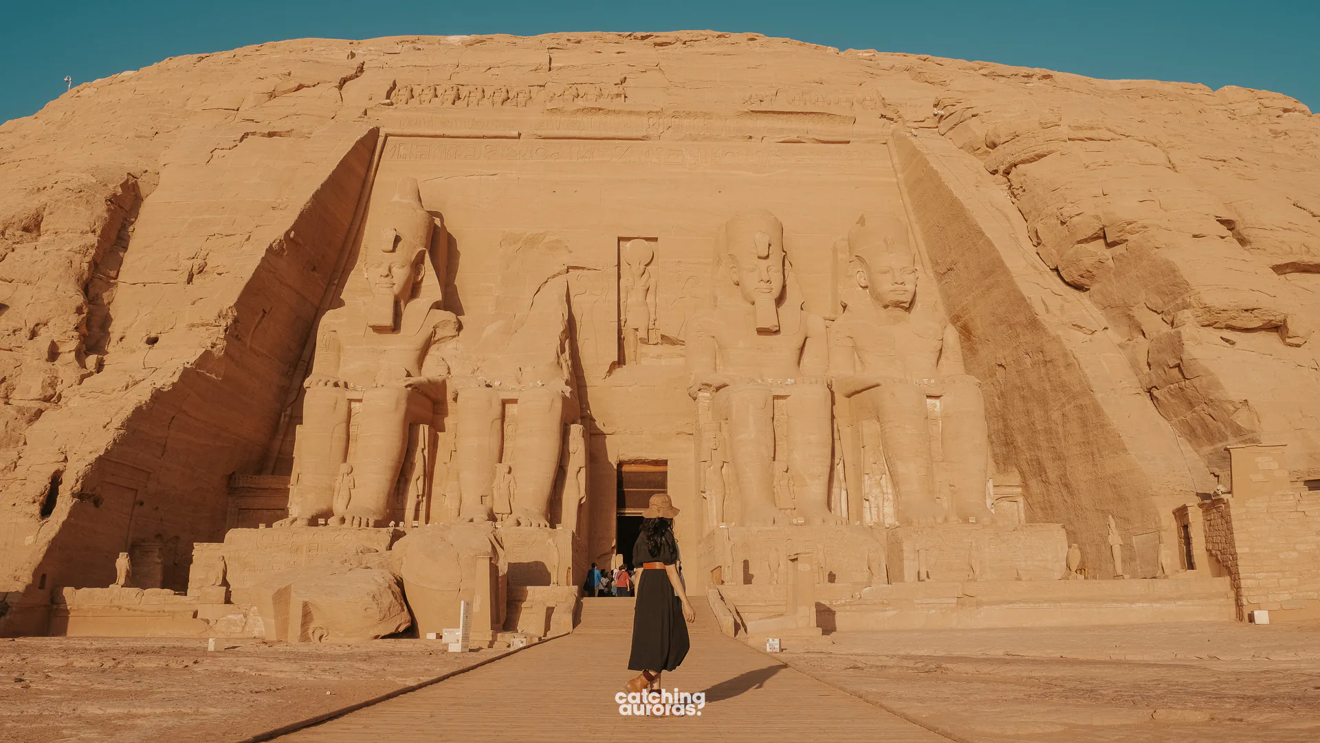 Traveller in a black dress standing before the Great Temple of Abu Simbel in Egypt