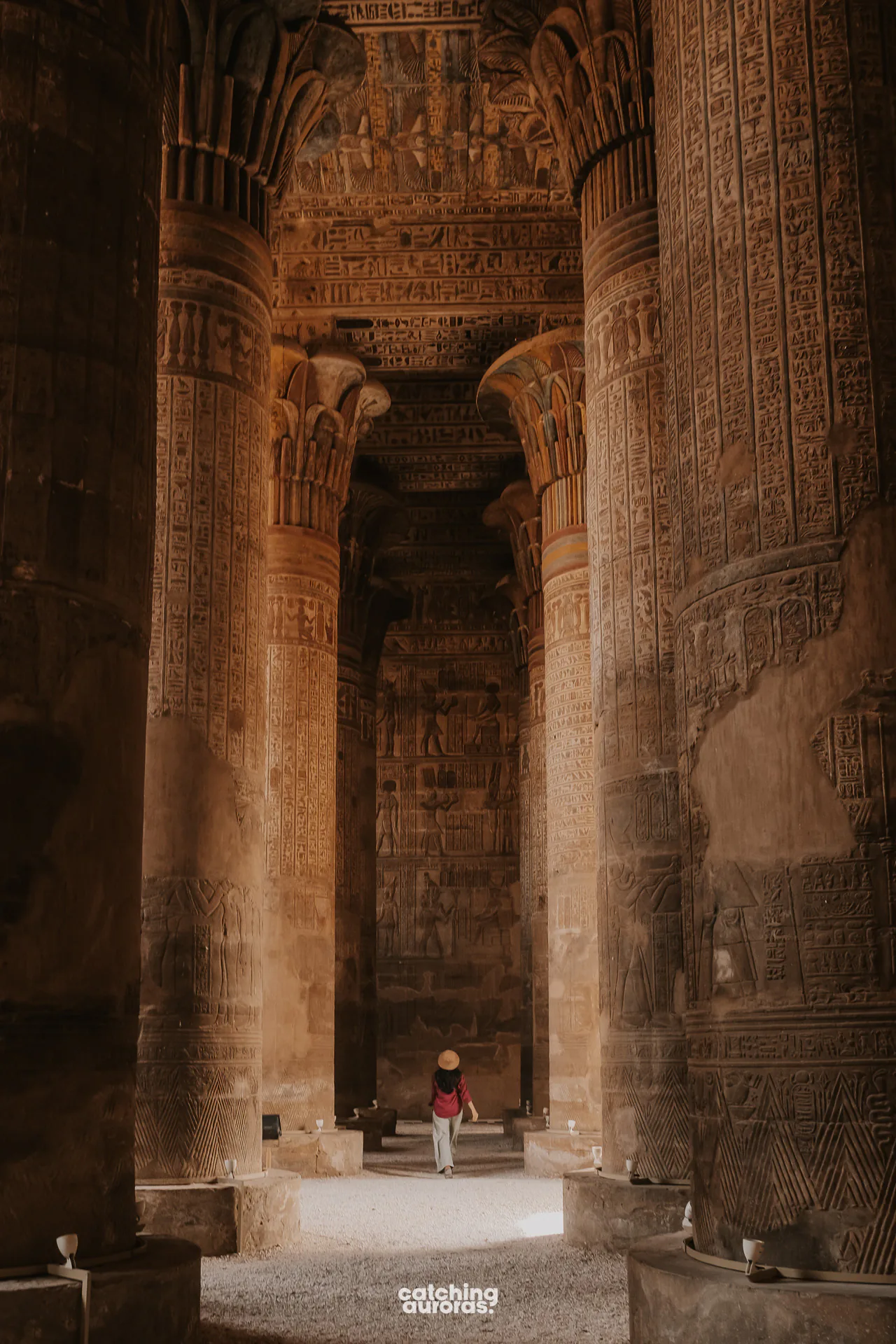 Traveller standing among the painted columns inside Esna Temple.