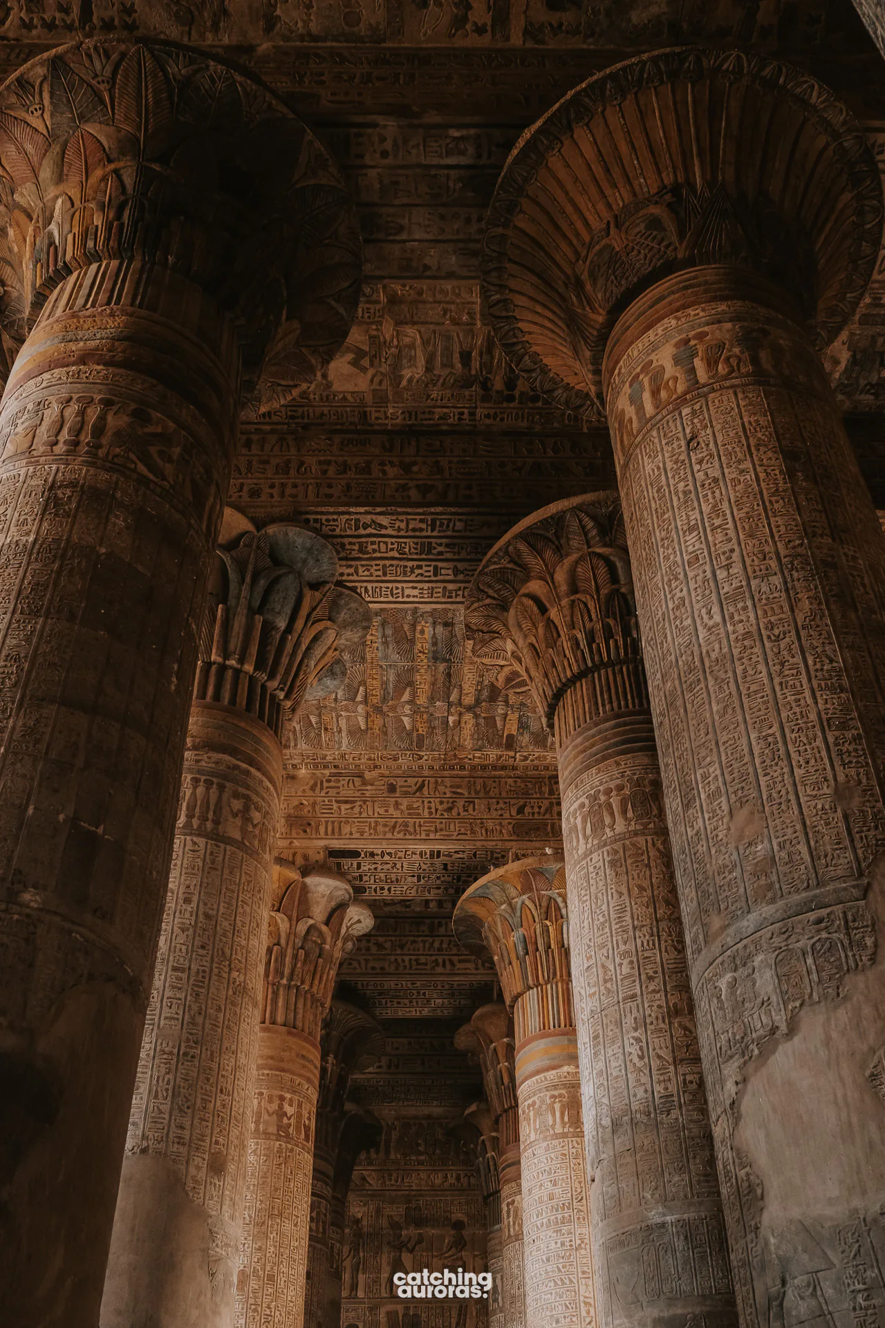 Traveller standing among the painted columns inside Esna Temple.