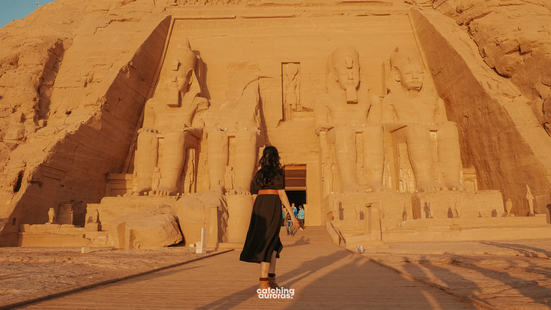 Woman in a black dress in front of the colossal statues of Ramesses II at Abu Simbel